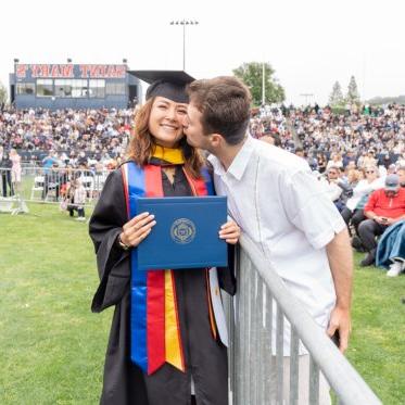 A graduating student being kissed on the cheek