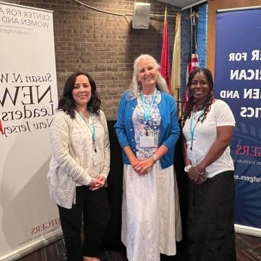 three attendees of CAWP in front of banners