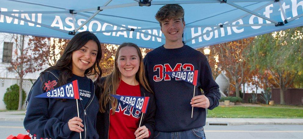 three students smiling outside