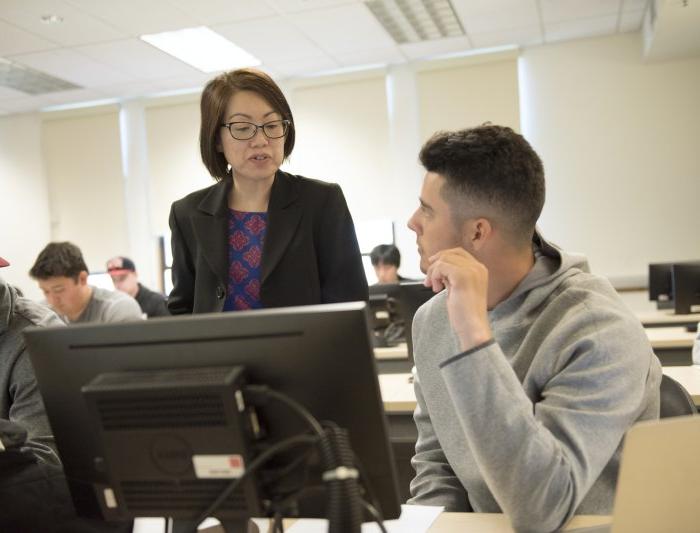 A professor talking to a student at a desk