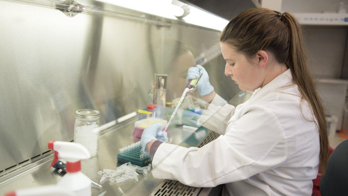 A female student wearing a lab coat is doing a science experiment  